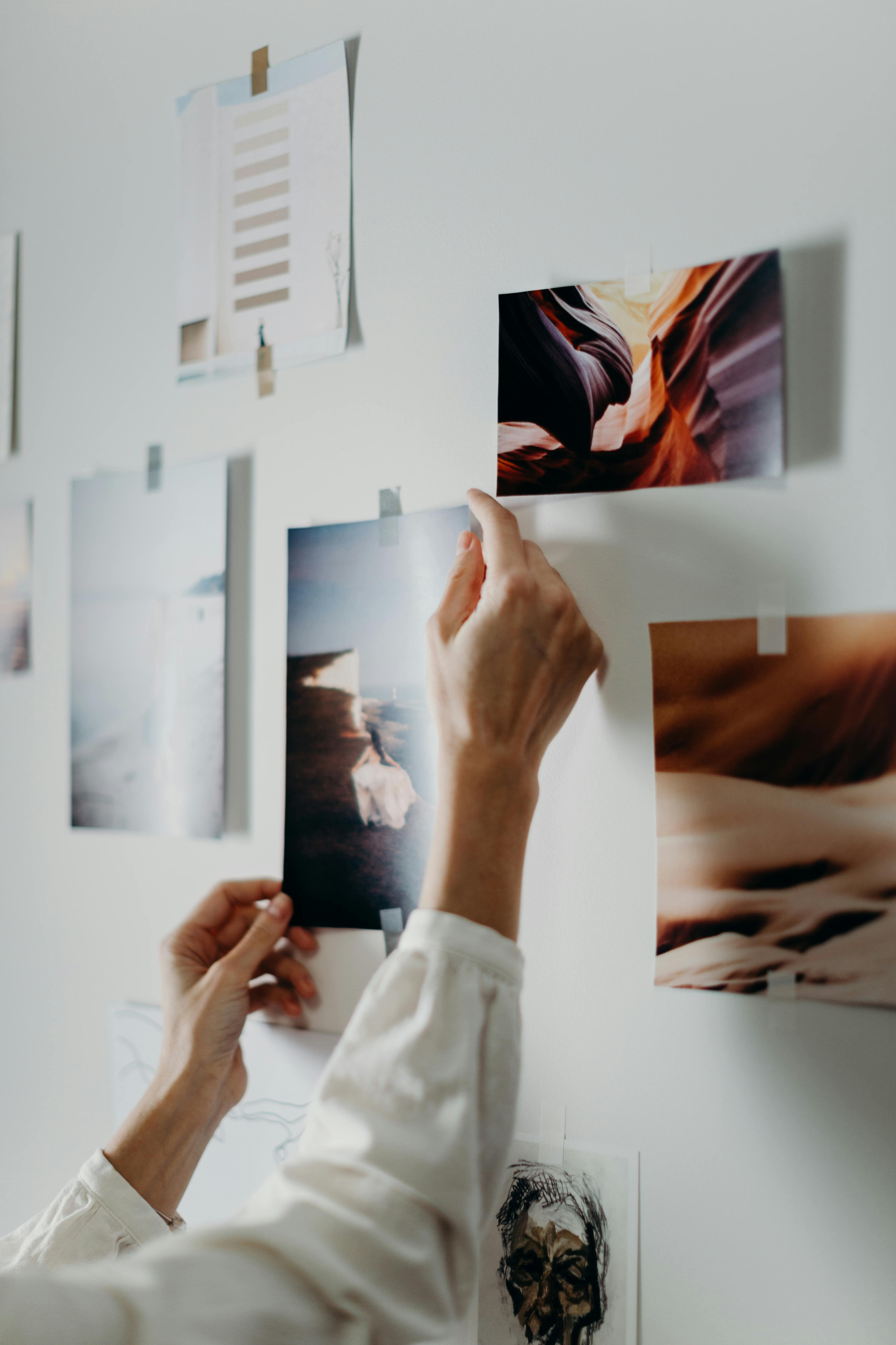 Hands taping photos into a collage design on a wall