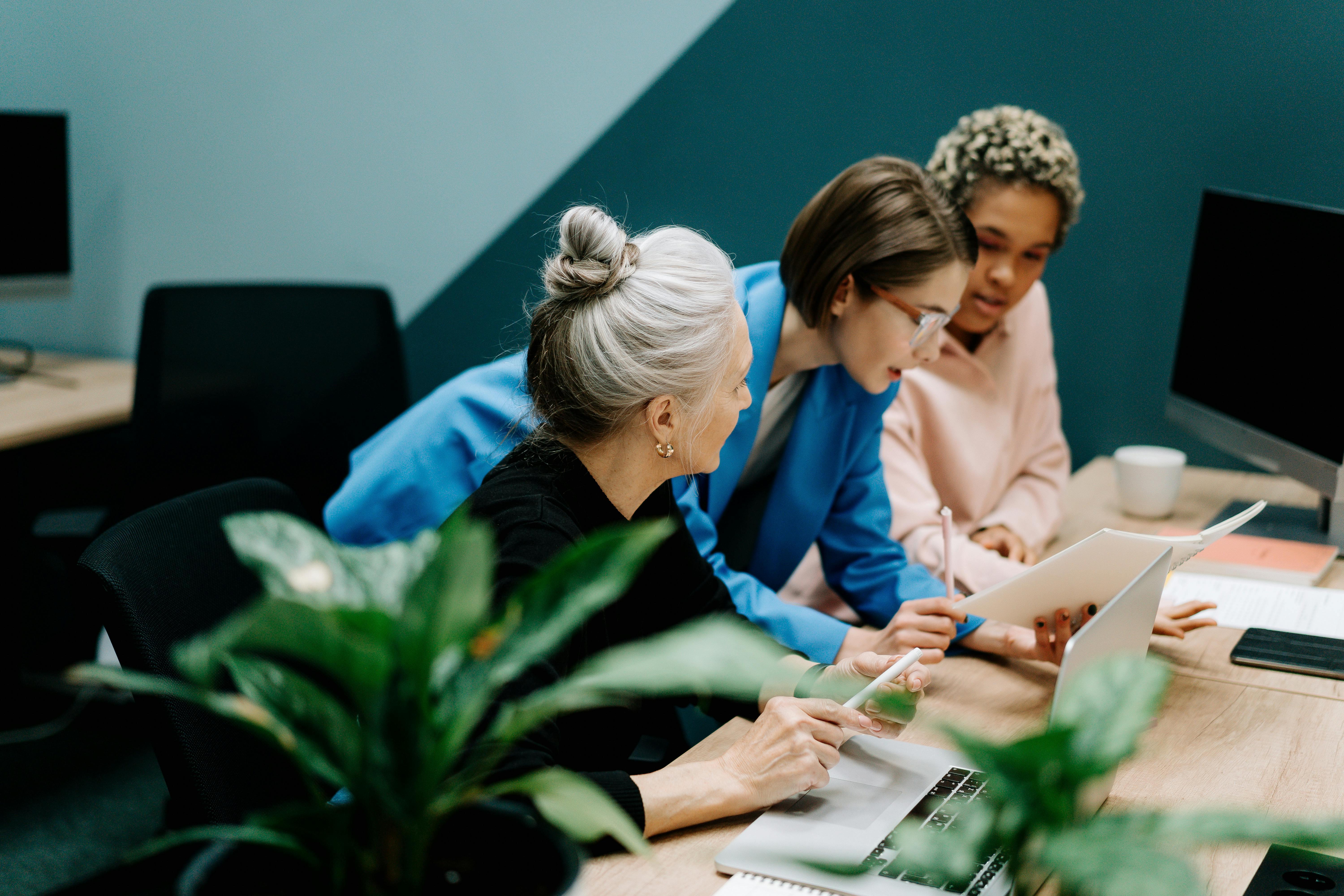 Three individuals working together on a plan at a desk